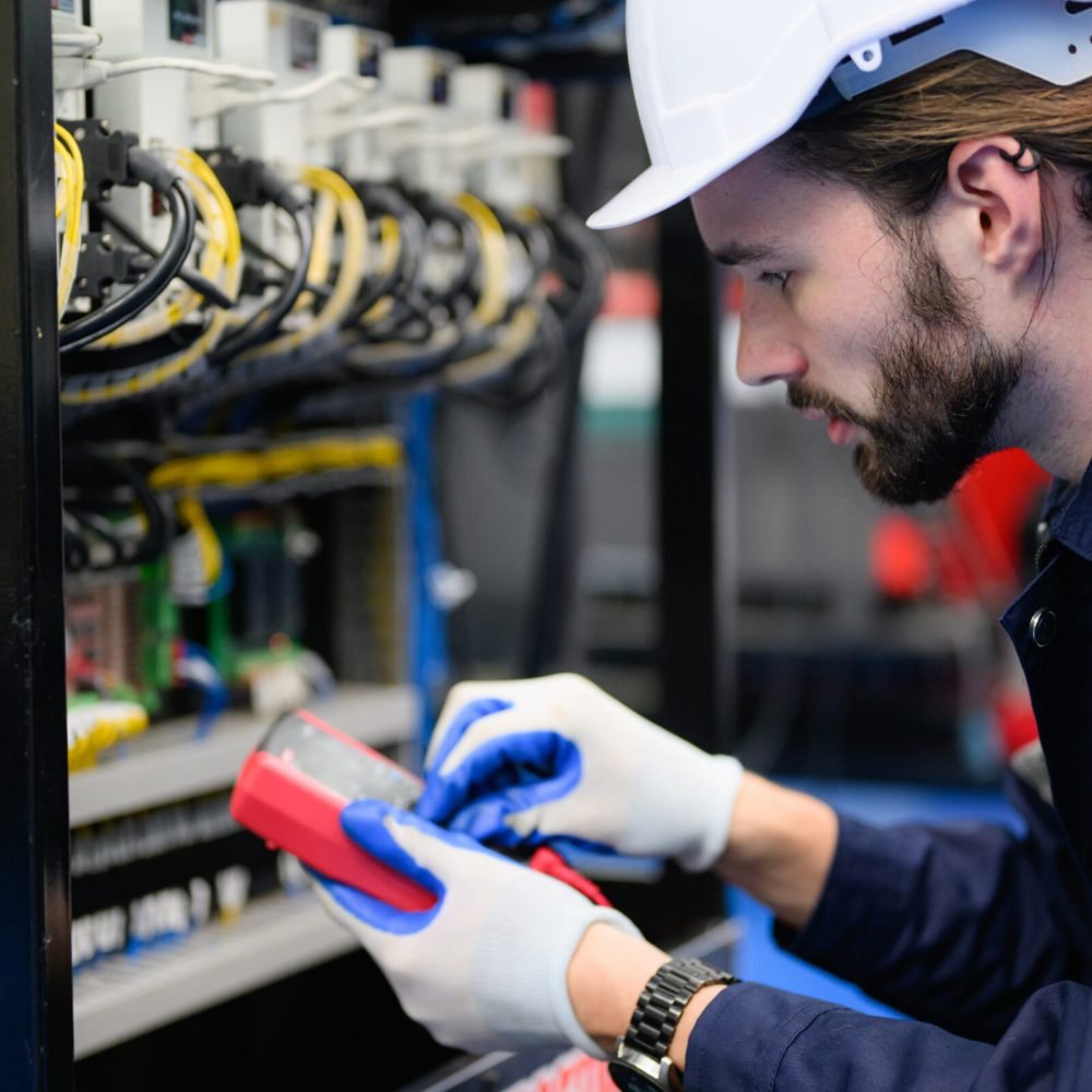 Professional technician checking and repairing part of automatic machine at industrial factory